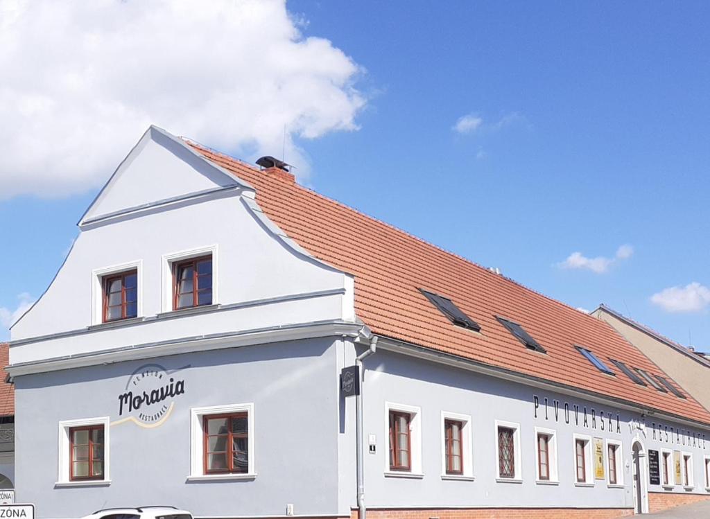 een wit gebouw met een rood dak bij Penzion pivovarská restaurace Moravia in Brno