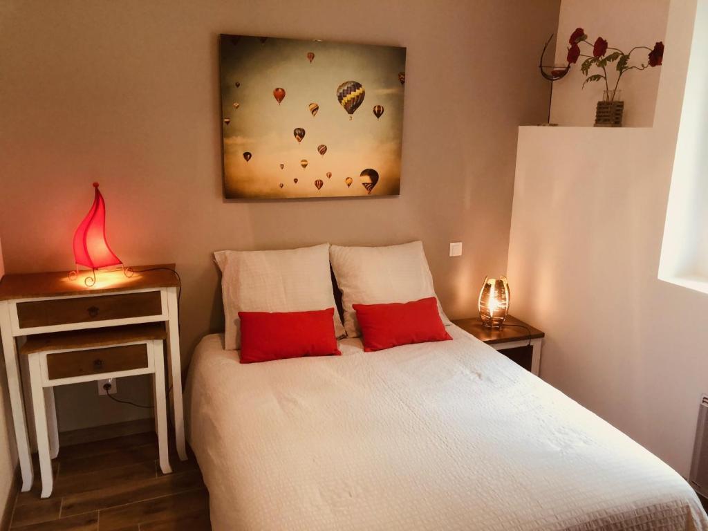 1 dormitorio con 1 cama con 2 almohadas rojas en la Sainterie, en Savonnières