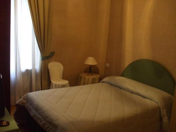 a bedroom with a bed and two chairs and a window at Albergo Bergagna in Pont Canavese
