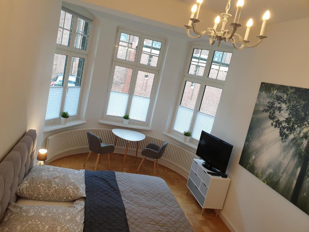 a bedroom with a bed and a tv and windows at Apartment Villa Kronenberg in Bochum