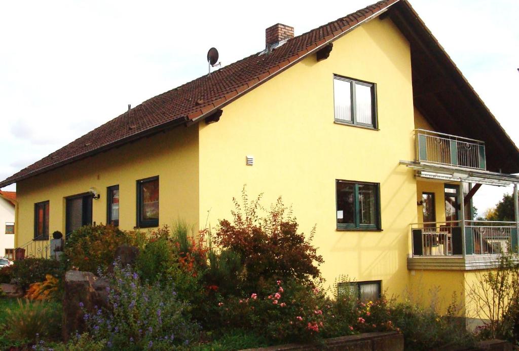 a yellow house with a balcony on the side of it at Ferienwohnung Glückstein in Großeibstadt