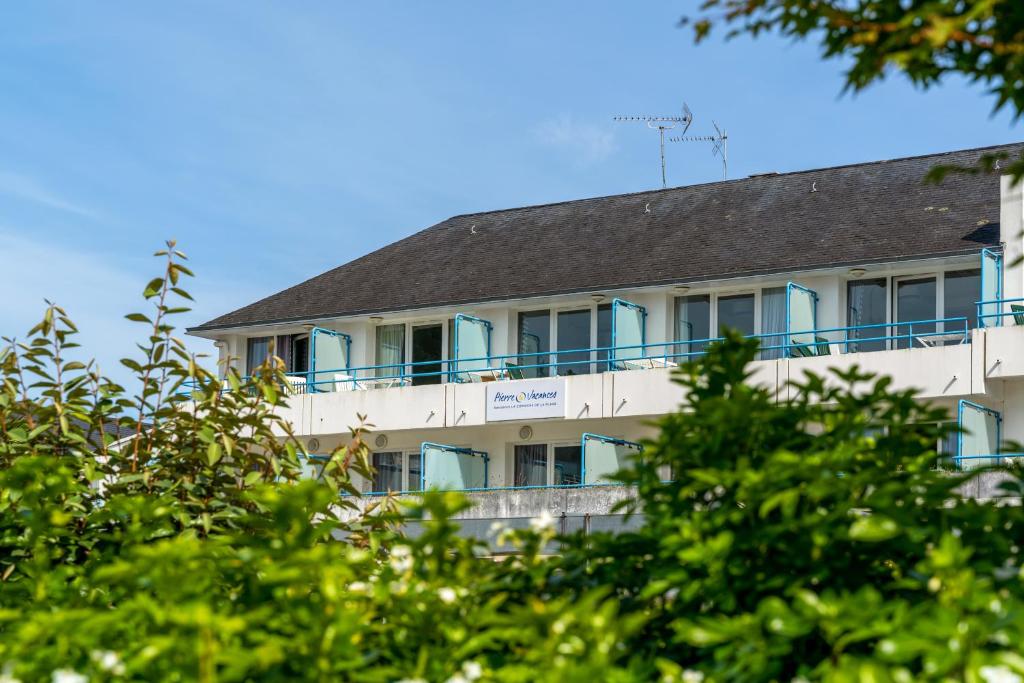 un bâtiment avec un balcon avec des arbres au premier plan dans l'établissement Résidence Pierre & Vacances la Corniche de la Plage, à Bénodet