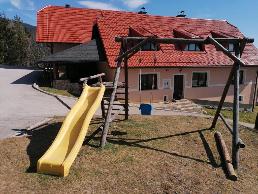 a playground with a yellow slide in front of a house at Apartment House Koprivnik in Zreče