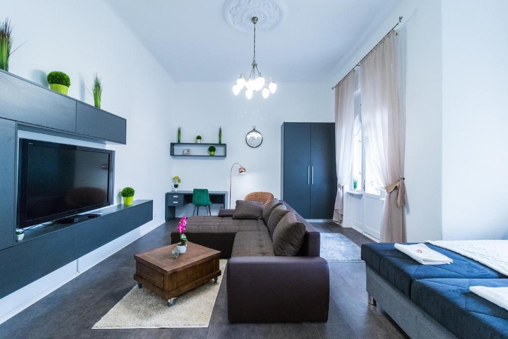 ein Wohnzimmer mit einem Sofa und einem TV in der Unterkunft Gróf palace Apartman in Szeged