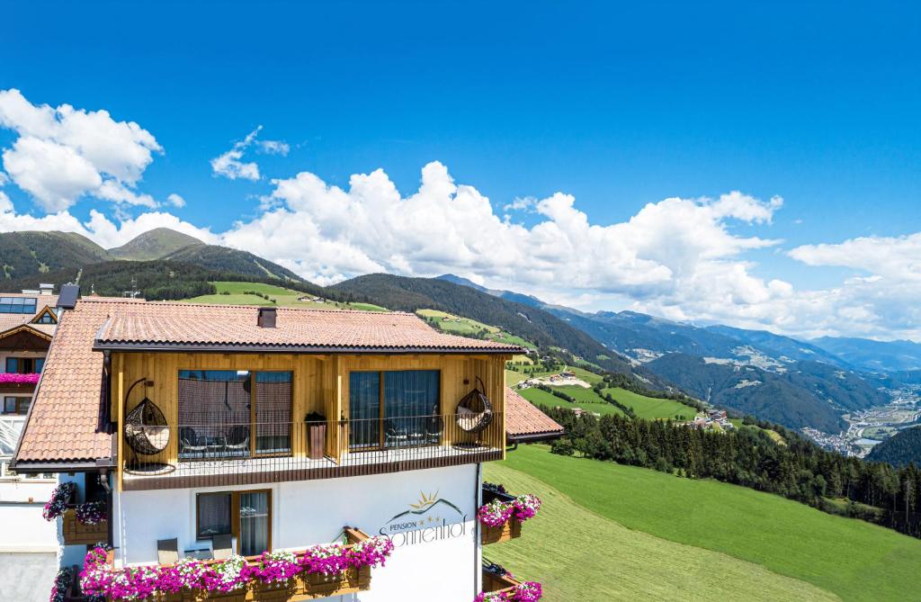 una casa in cima a una collina con dei fiori di Pension Sonnenhof a Maranza