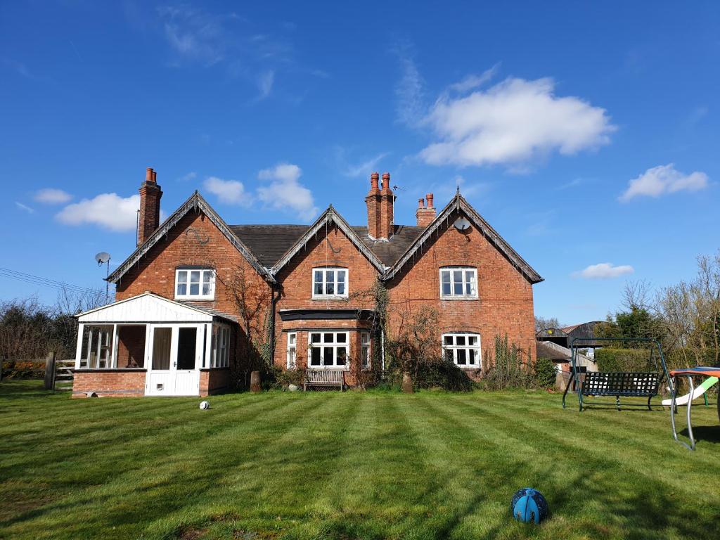 a large brick house with a large grass yard at Church Farm Accommodation in Bickenhill