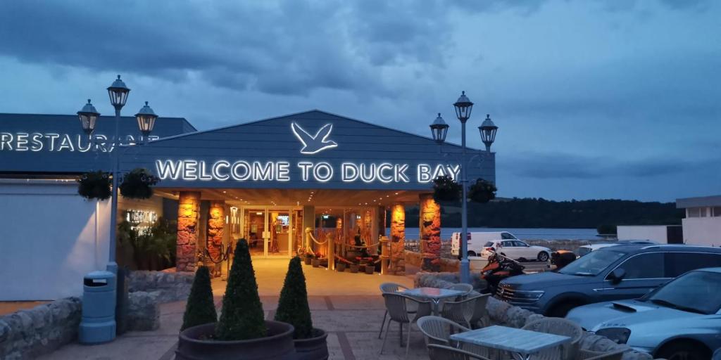 巴洛赫的住宿－Duck Bay Hotel & Restaurant，一座建筑,上面有标志,上面写着欢迎客人去鸭湾