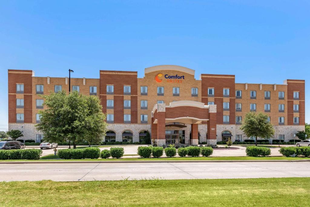 a large red brick building with a sign on it at Comfort Suites Frisco in Frisco