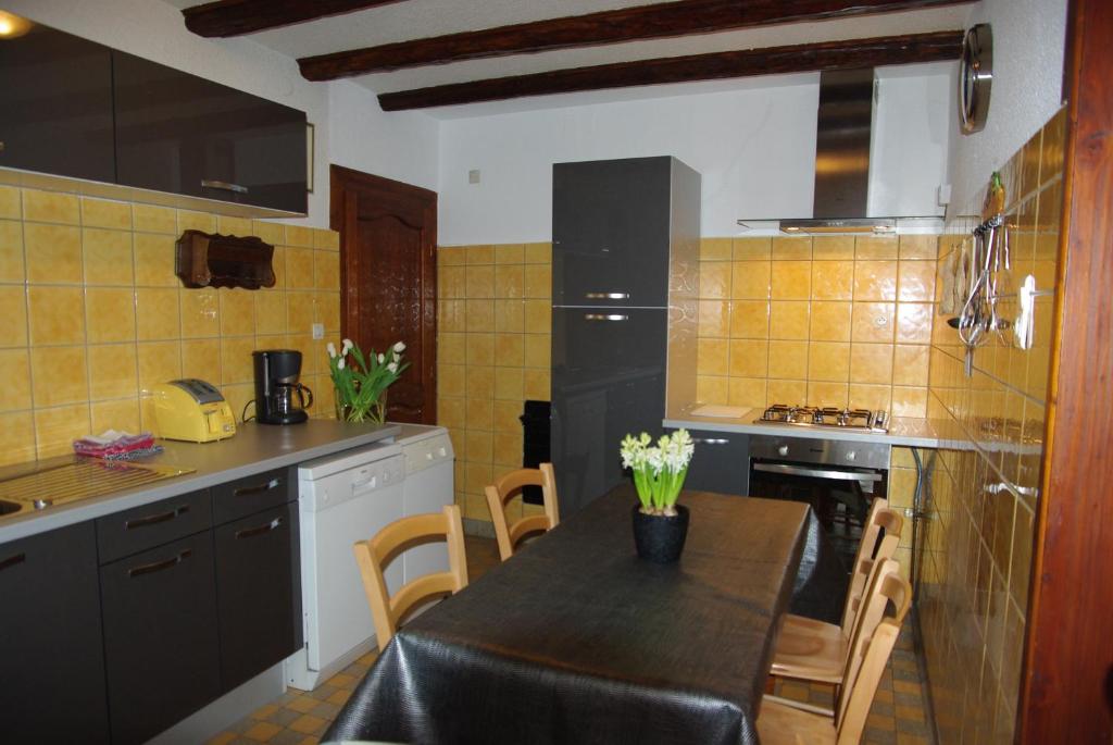 アンマーシュヴィアにあるGîte Le Merle 90m2 près de la route des vinsのテーブル付きのキッチン、黄色のタイルのキッチンが備わります。