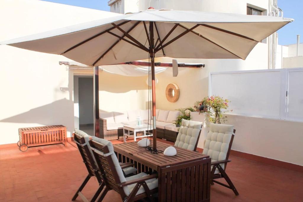 a wooden table with an umbrella on a patio at VV Canteras Oasis "by henrypole home" in Las Palmas de Gran Canaria