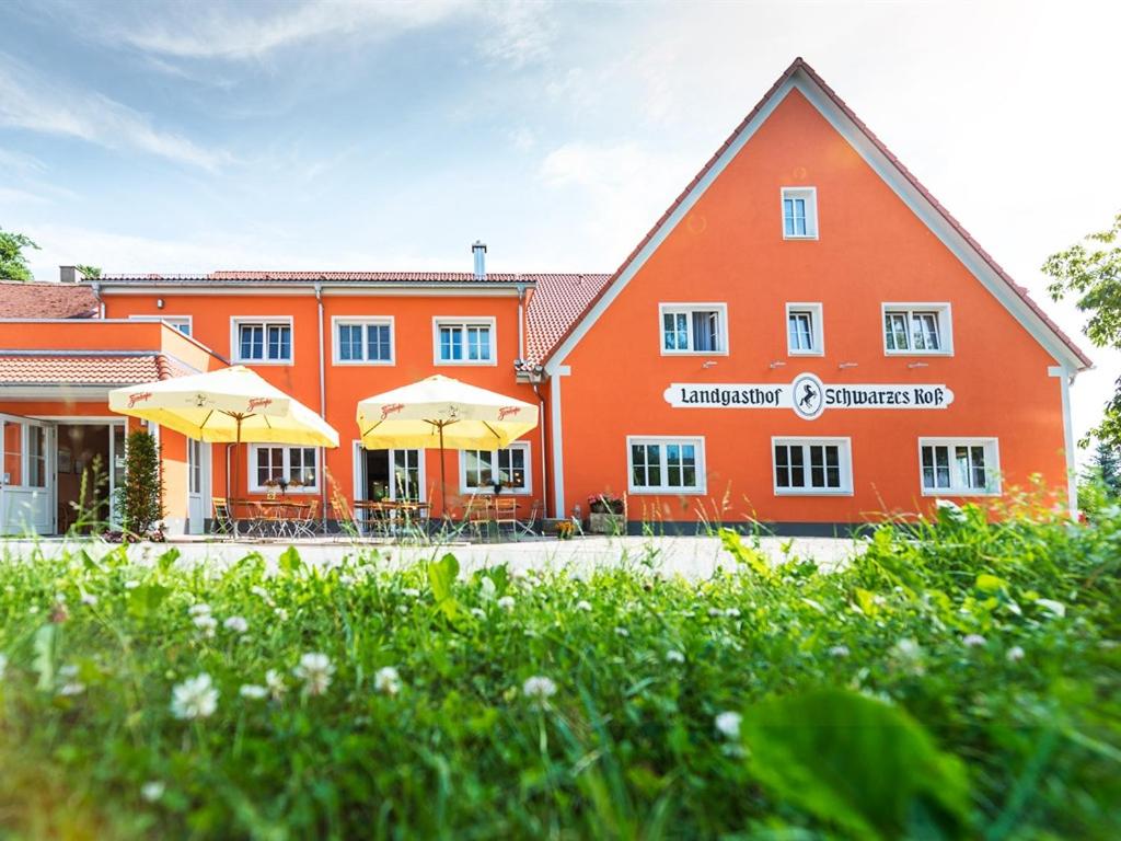 a large orange building with umbrellas in front of it at Landgasthof Schwarzes Roß in Ansbach