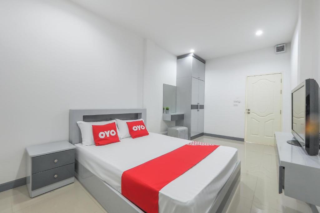 una camera con un grande letto con cuscini rossi e una TV di OYO 1159 K&k Apartment a Samutprakarn