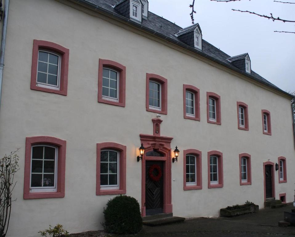 uma casa branca com janelas vermelhas e uma porta em Ferienwohnung Jacobshof em Oberstedem