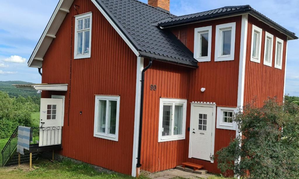 a red house with white windows and a black roof at Symaskinshuset Järvsö in Järvsö