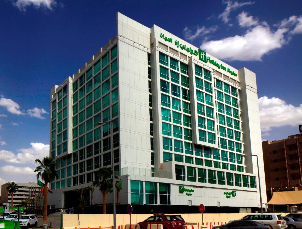 um grande edifício branco com janelas verdes numa rua da cidade em Holiday Inn Meydan, an IHG Hotel em Riyadh