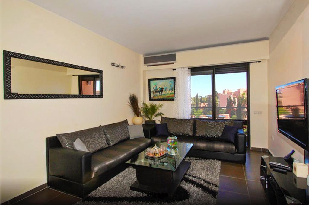 a living room with a black leather couch and a mirror at Ghita Appartement in Marrakesh
