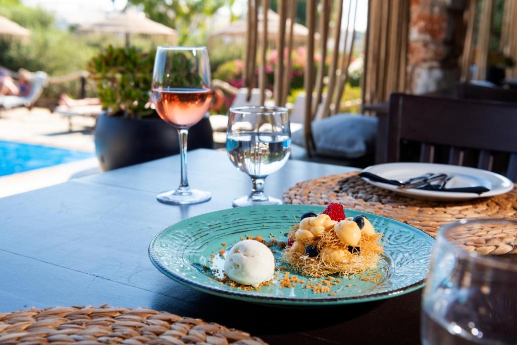 a table with a plate of food and a glass of wine at Parosland Hotel in Aliki