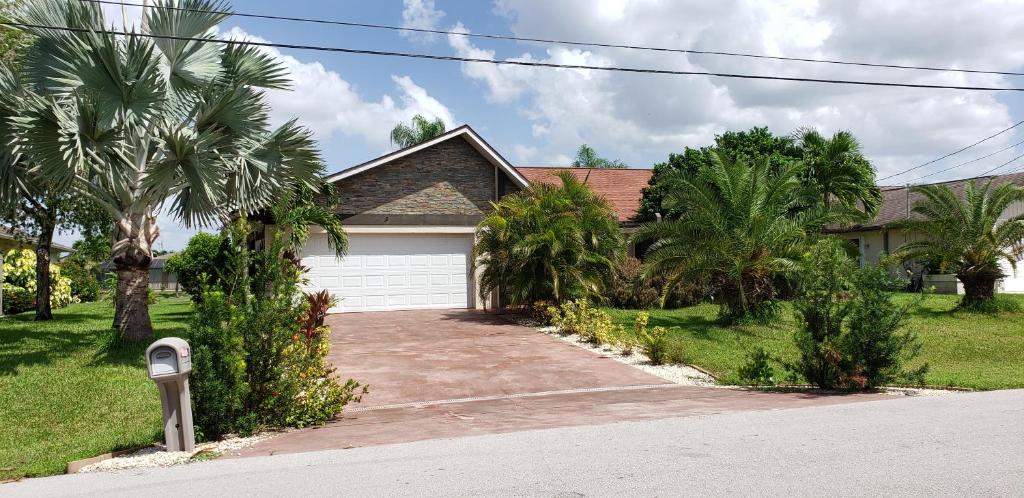 a house with a garage and palm trees at Sunny Paradise in Cape Coral