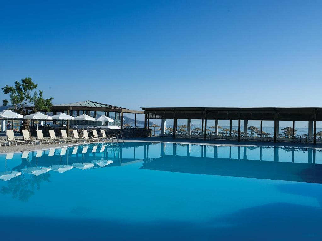 a large swimming pool with chairs and umbrellas at Atlantica Akti Zeus Hotel in Amoudara Herakliou