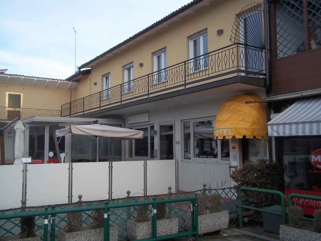 un bâtiment avec une clôture et un parasol devant lui dans l'établissement Hotel Gronda Lagunare, à Tessera