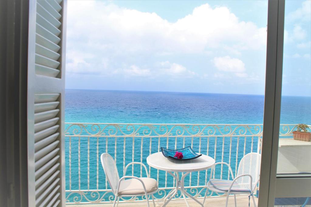 balcone con tavolo, sedie e vista sull'oceano di Appartamento Diamante a Tropea