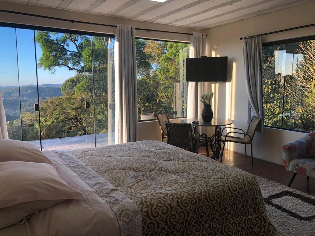um quarto com uma cama e uma grande janela em Villa Platô em Monte Verde
