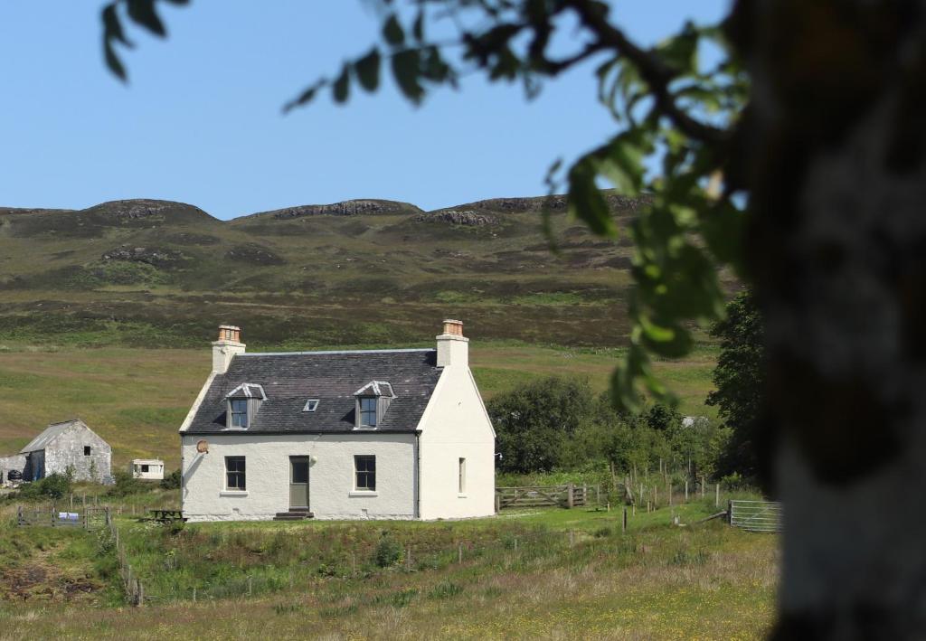 una vieja casa blanca en medio de un campo en Dunvegan Castle The Farmhouse Cottage, en Dunvegan