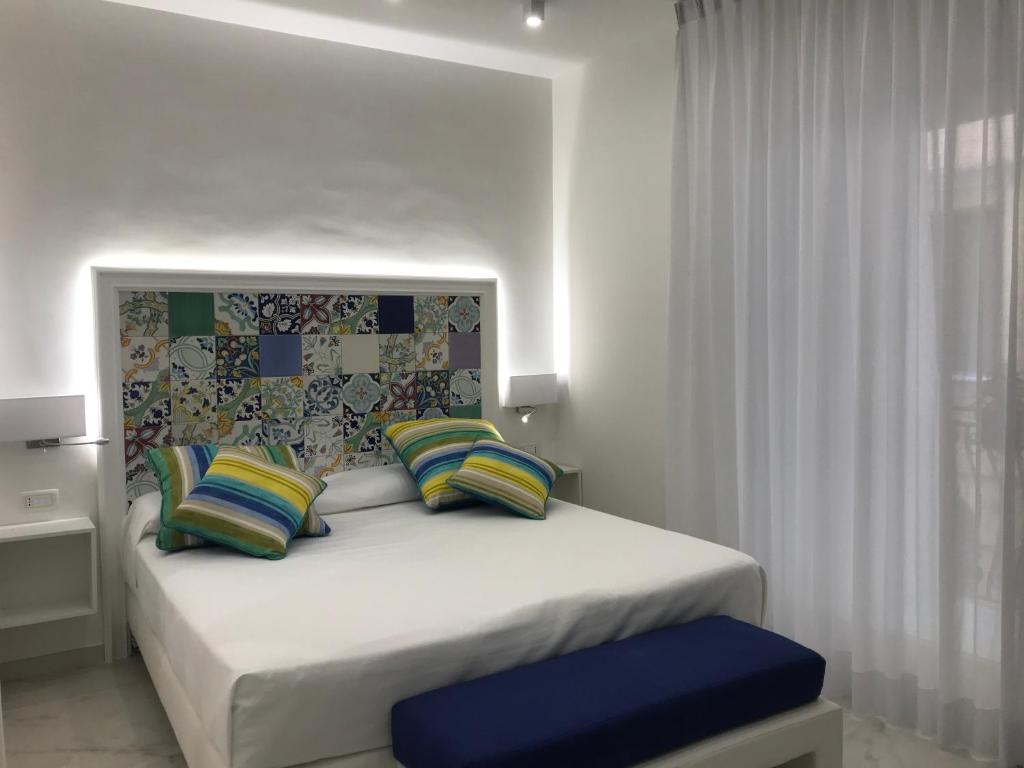 a bedroom with a white bed with colorful pillows at Amalfi Suite Boutique Hotel in Amalfi