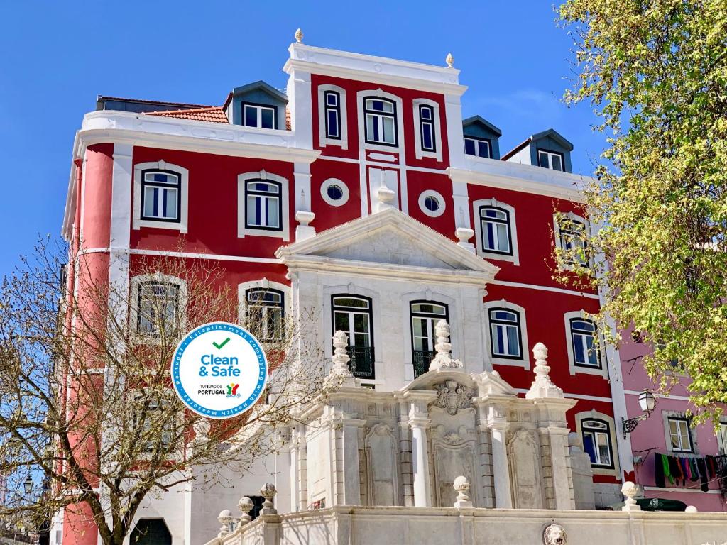 een rood-wit gebouw met een bord erop bij Hermitage Castelo - Casa Chafariz in Lissabon