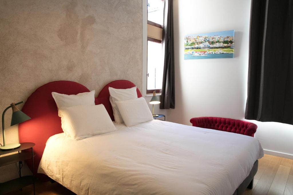 圖爾尼的住宿－Spacieux appartement, A-mi-chemin, au coeur de Tournus，卧室配有白色的床和红色椅子