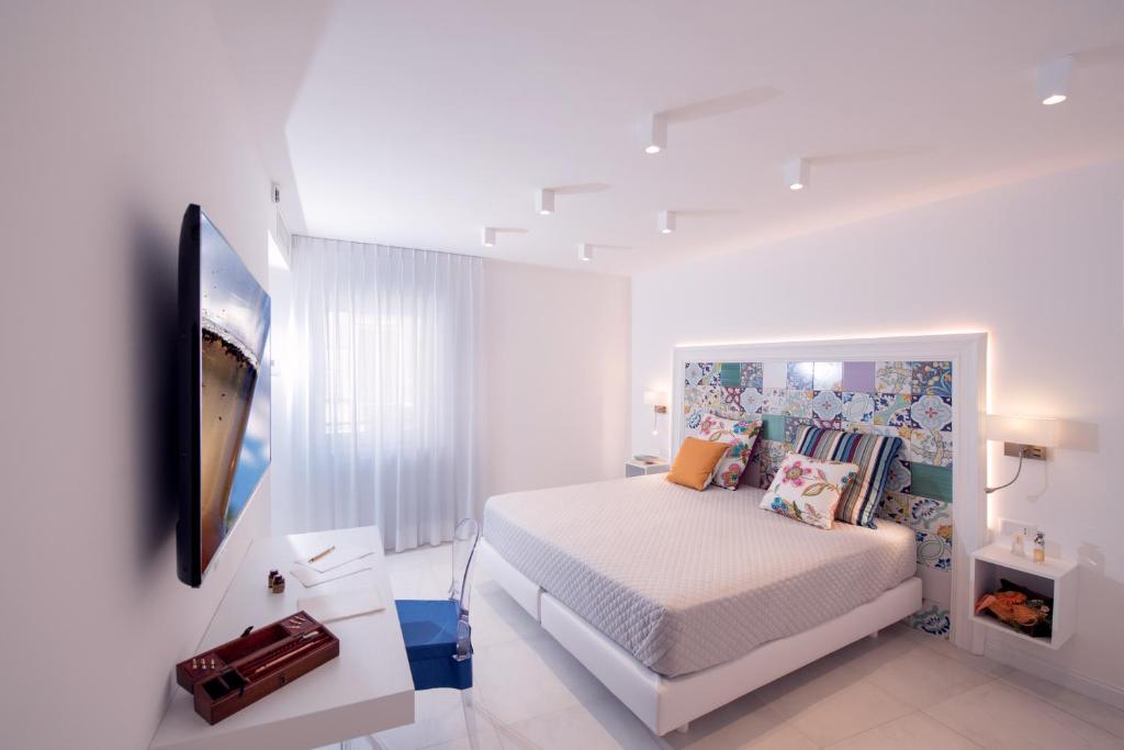 a white bedroom with a bed and a tv at Amalfi Suite Boutique Hotel in Amalfi