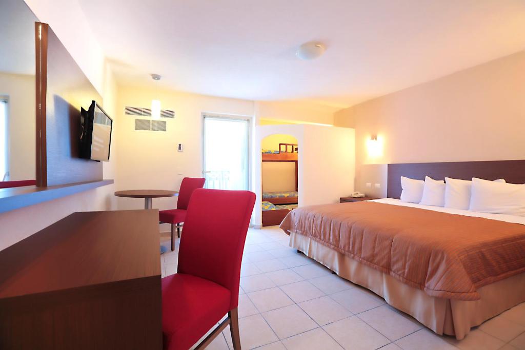 une chambre d'hôtel avec un lit et un fauteuil rouge dans l'établissement Crown Paradise Club All Inclusive, à Puerto Vallarta