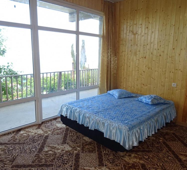 a bedroom with a bed and a large window at Гостевой дом с видом на море in Gagra