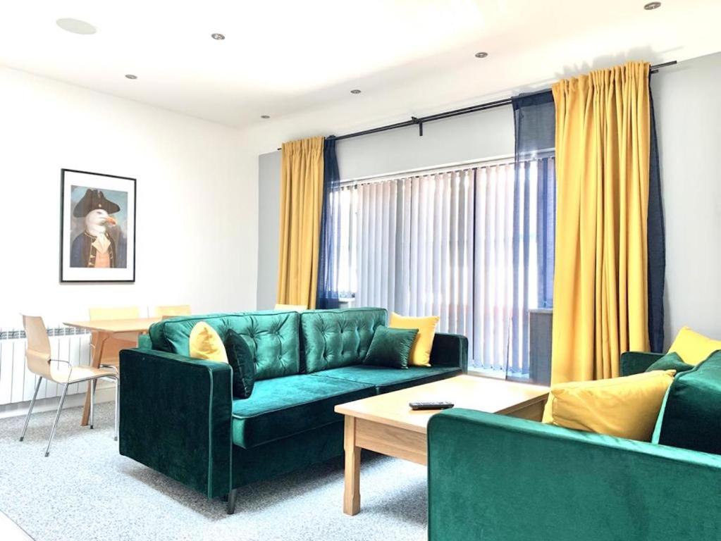 a living room with a green couch and a table at Premium Apartments Thatcham Broadway in Thatcham