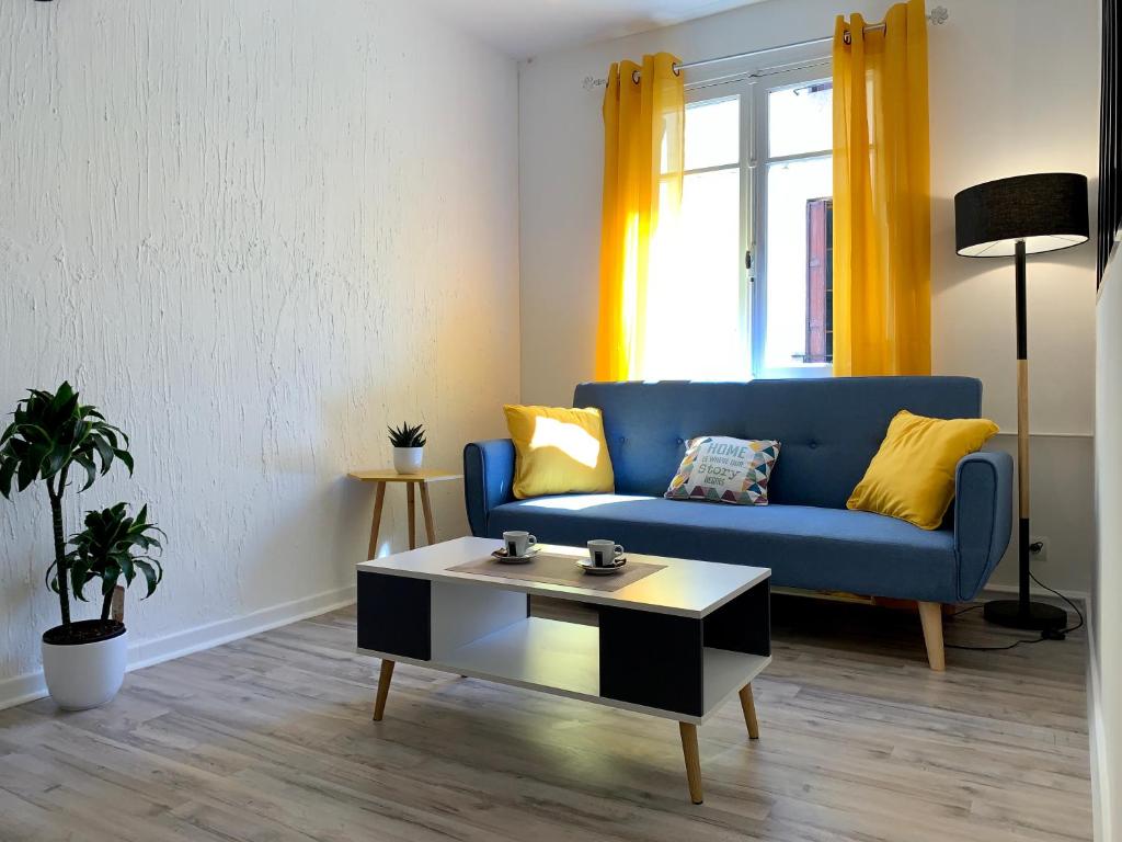 uma sala de estar com um sofá azul e uma mesa de centro em Appartements Voltaire - Carcassonne Centre em Carcassonne