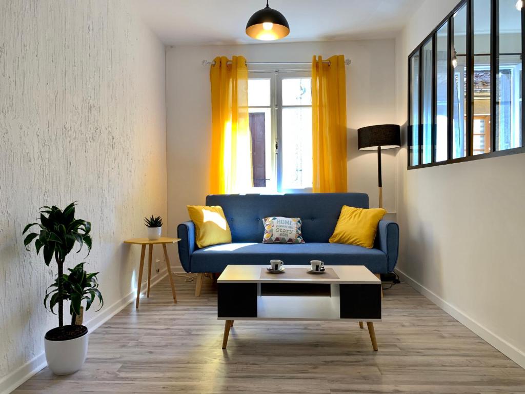 a living room with a blue couch and a coffee table at Appartements Voltaire - Carcassonne Centre in Carcassonne