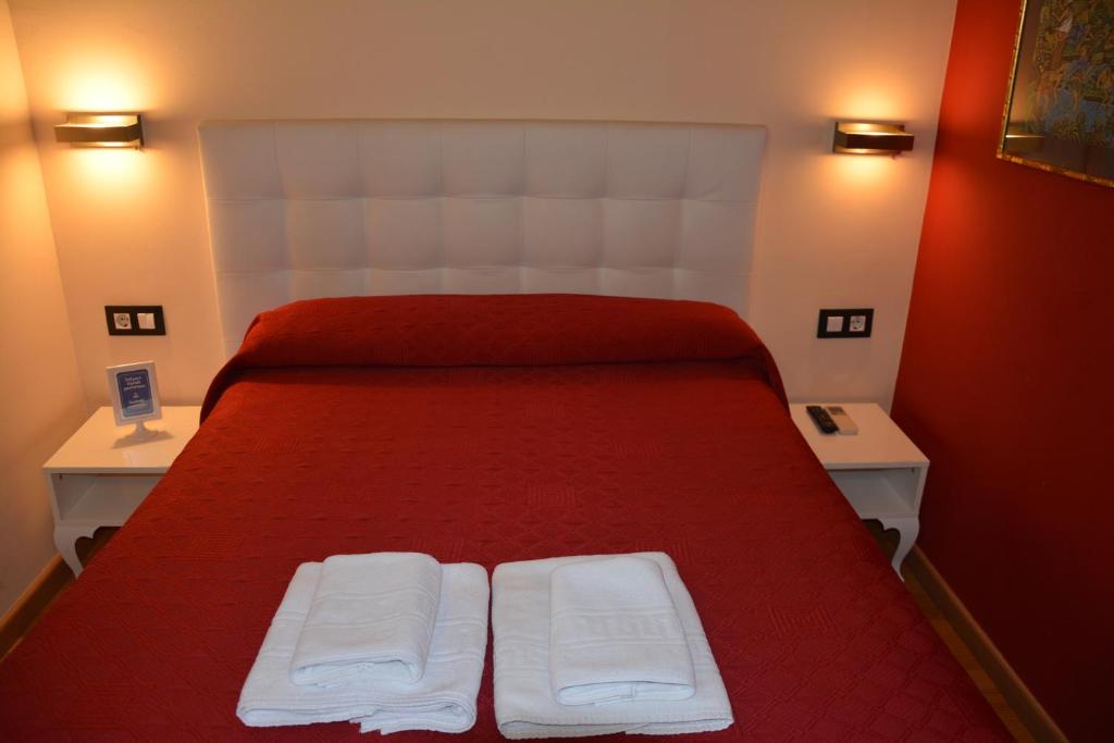 a bedroom with a red bed with two white towels on it at Center Gran Via in Barcelona