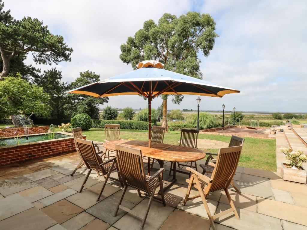 une table et des chaises avec un parasol sur une terrasse dans l'établissement Waveney View Cottage, à Great Yarmouth