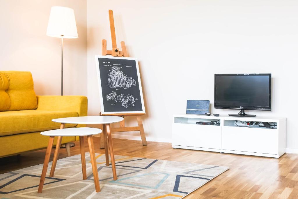 a living room with a couch and a table and a tv at Dziesiąte Piętro in Poznań