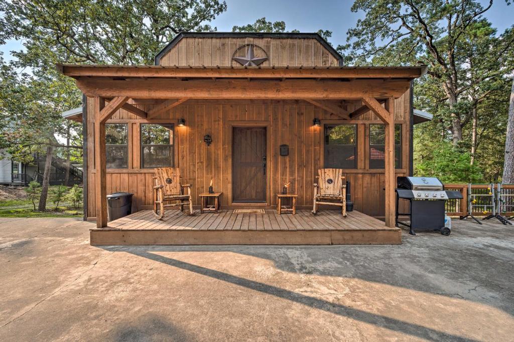 a wooden cabin with two chairs and a grill at Western Daze Broken Bow Cabin in Hochatown! in Stephens Gap