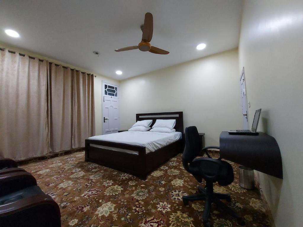 a bedroom with a bed and a ceiling fan at Hotel Astro in Gilgit
