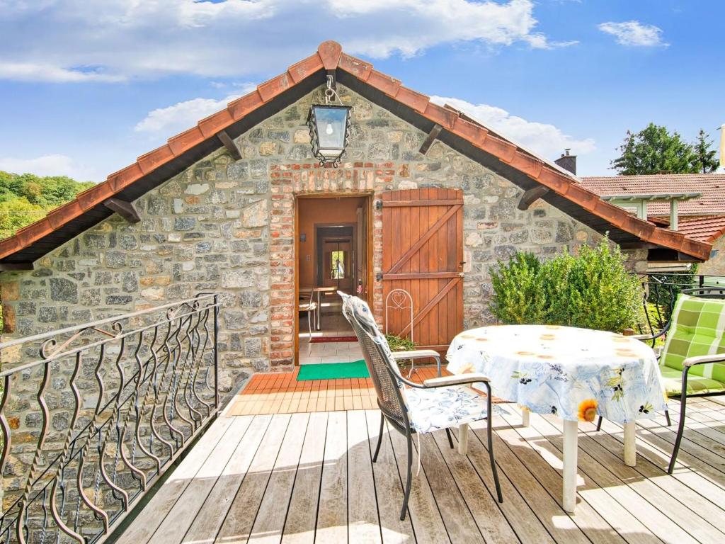 a stone cottage with a table and chairs on a deck at Enjoy a relaxing break for two and discover Durbuy in Biron
