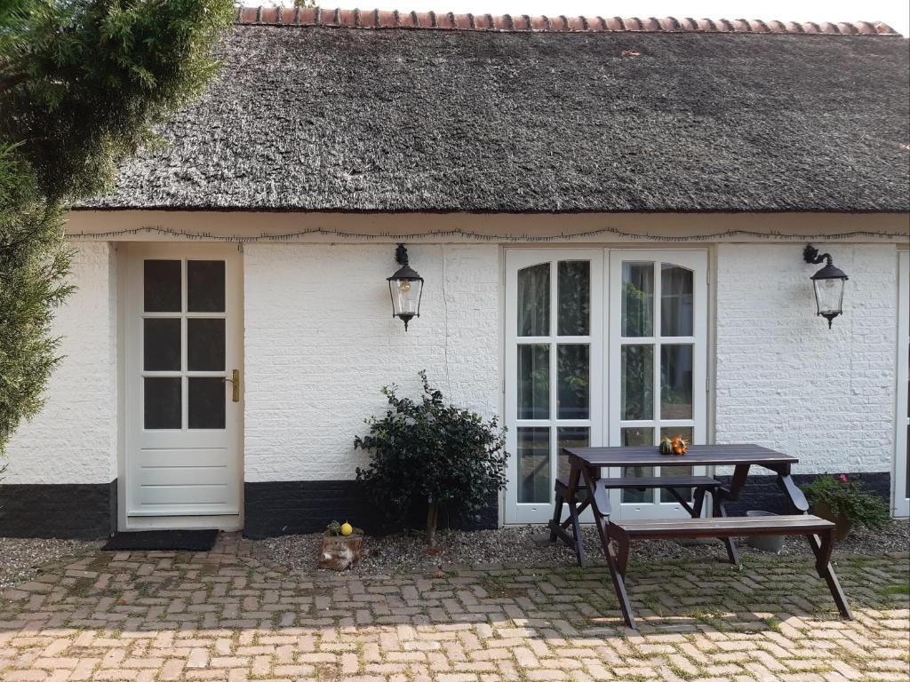 une maison blanche avec une table de pique-nique devant elle dans l'établissement Bij de Vlaamse Schuur, à Wagenberg
