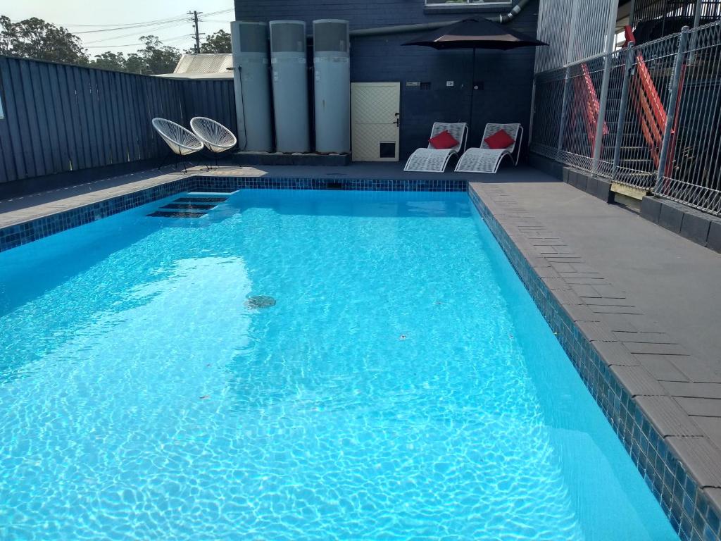 a swimming pool with blue water and chairs in it at Kew Motel in Kew