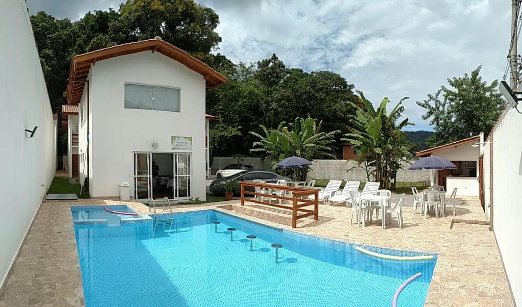 a swimming pool with a table and chairs next to a house at Pousada Recanto das Margaridas in Boicucanga