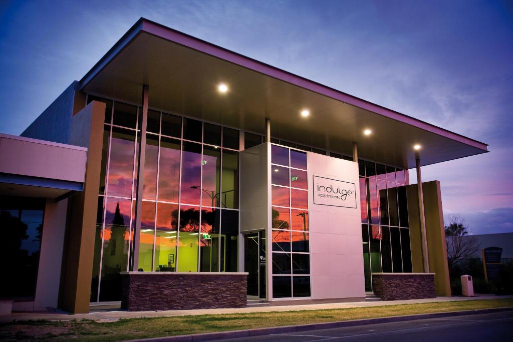 a large building with glass windows with a sunset at Indulge Apartments - Langtree in Mildura