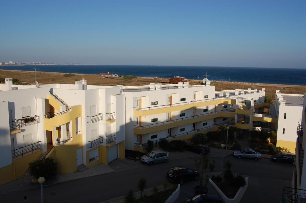 een appartementencomplex met een parkeerplaats naast de oceaan bij Clube Meia Praia in Lagos