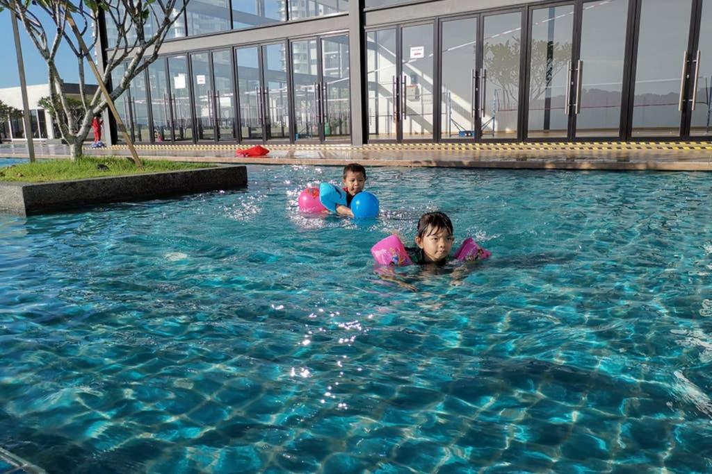 two children are swimming in a swimming pool at AniS Homestay Nilai USIM KLIA INTI Manipal Nilai 3 in Nilai