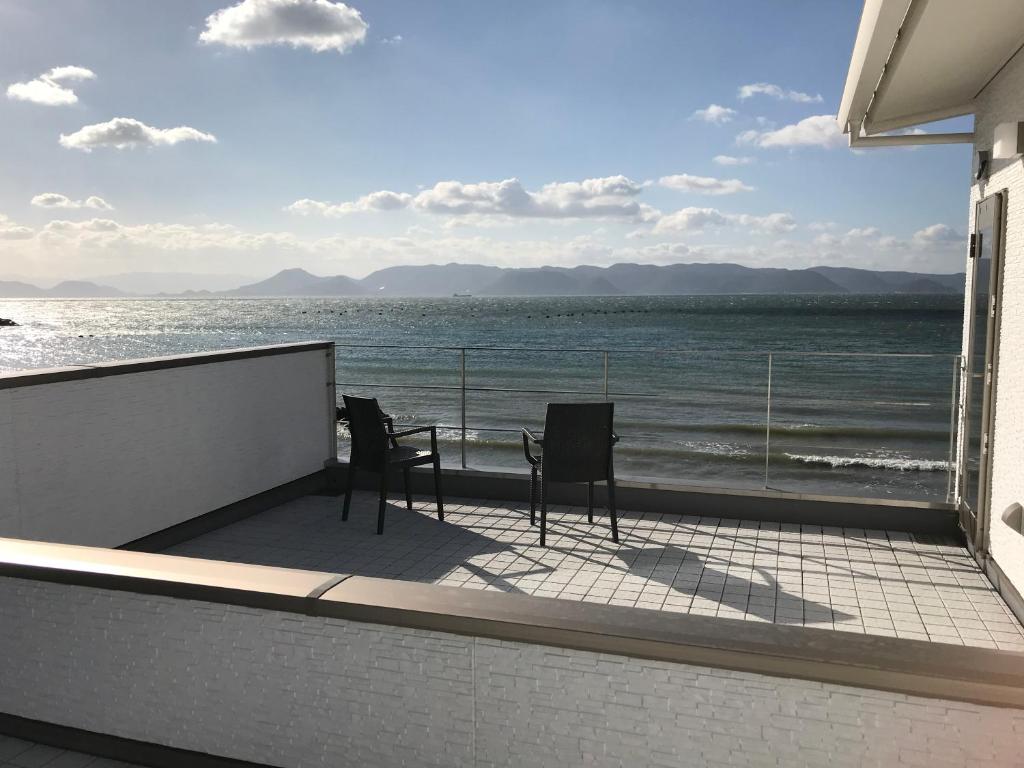 two chairs and a table on a balcony overlooking the ocean at UOGASHI 7070 Ocean View in Naoshima