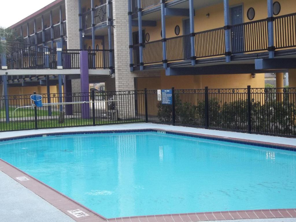 a large blue swimming pool in front of a building at Scottish Inns Galveston in Galveston